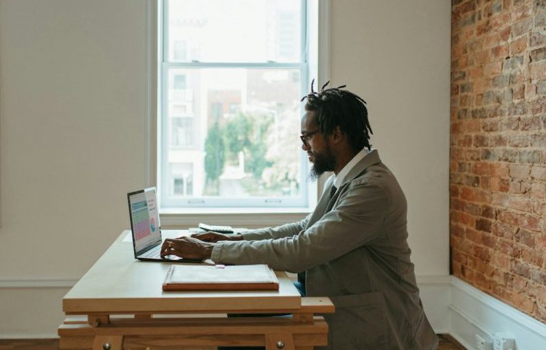 Remote Work - a person sitting at a desk with a laptop and papers