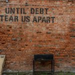 Debt Consolidation - Until debt tear us apart printed red brick wall at daytime