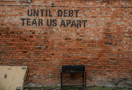 Debt Consolidation - Until debt tear us apart printed red brick wall at daytime