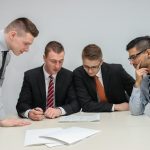 Financial Discussion - four men looking to the paper on table