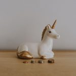 Real Estate Coins - white and gold ceramic unicorn figurine near coins