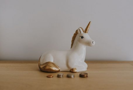 Real Estate Coins - white and gold ceramic unicorn figurine near coins