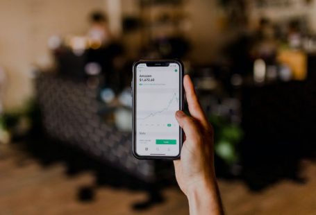 Short-term Investment - person holding black iPhone displaying stock exchange