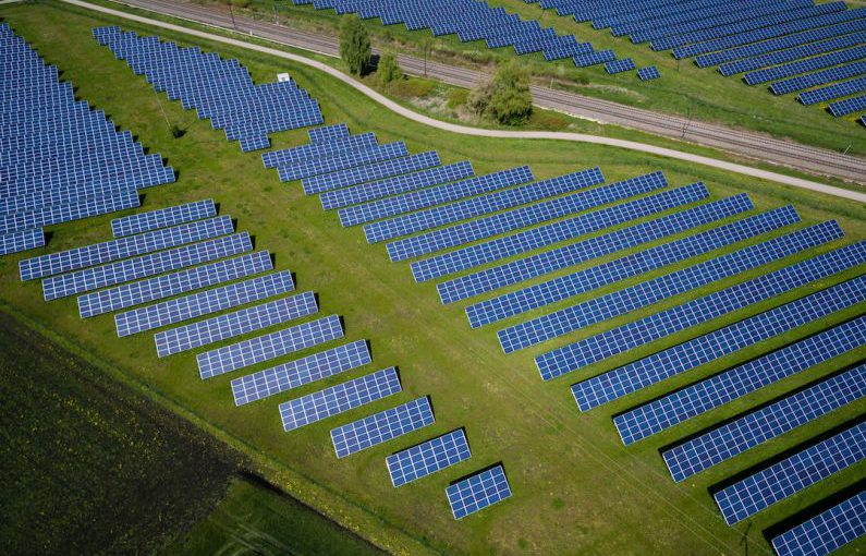Renewable Energy - aerial photography of grass field with blue solar panels