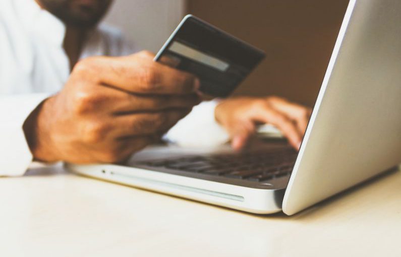 Online Banking - person using laptop computer holding card