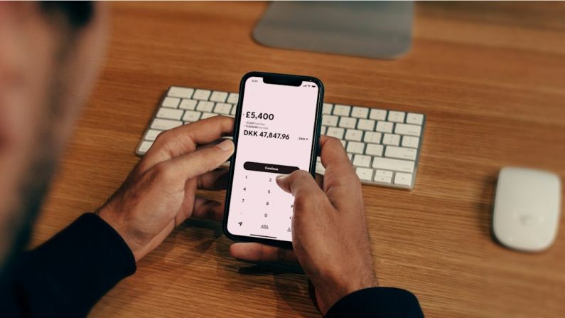 Finance Apps - a man holding a cell phone in front of a keyboard